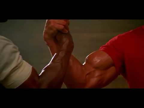 Dillon and Dutch in the first Predator film locking hands in an arm wrestling form and flexing